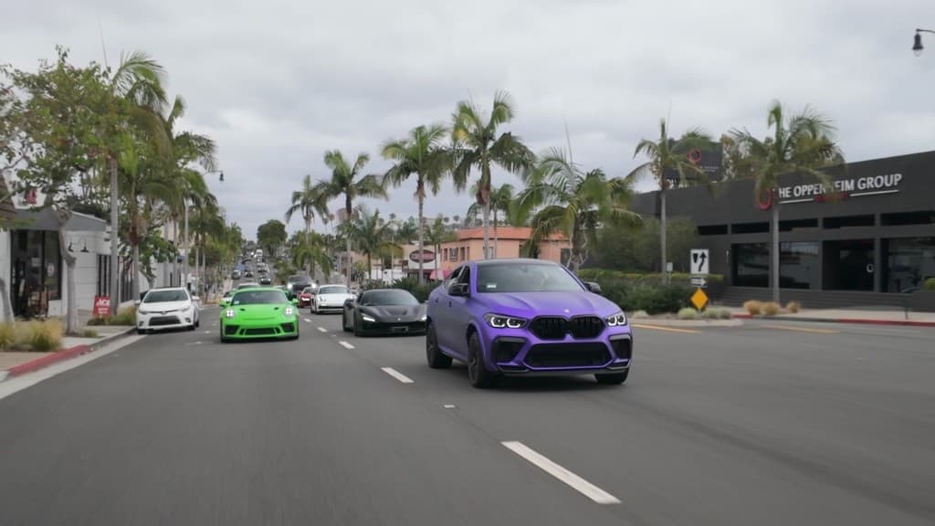 Luxury performance car convoy on a palm-lined street